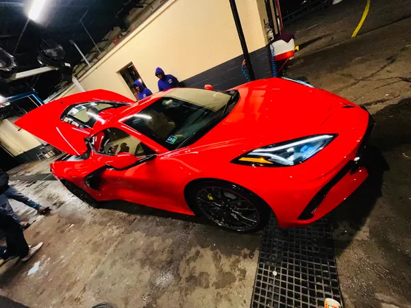 A red Corvette with its doors open in the wash bay